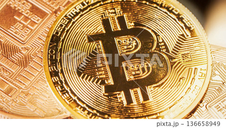 Bitcoin coin is shown in close up view with gold color and digital patterns on its surface under bright light in a modern setting. High quality photo 136658949