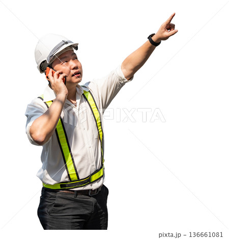 A construction engineer wearing a safety helmet and high visibility vest talking on the phone while pointing upwards giving instructions on a construction site. A construction engineer wearing a safety helmet and high visibility vest talking on the phone while pointing upwards giving instructions on a construction site. 136661081