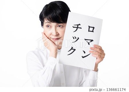 ロマンチックと書かれた紙を持ち頬に手をあて物思いにふけるシニア女性 ロマンチックと書かれた紙を持ち頬に手をあて物思いにふけるシニア女性 136661174