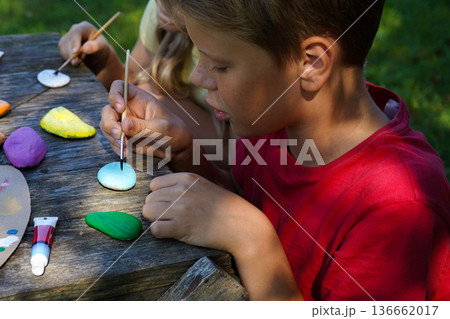 Painting stones becomes an act of sharing, as children craft vibrant, imaginative DIY gifts for special people. 136662017