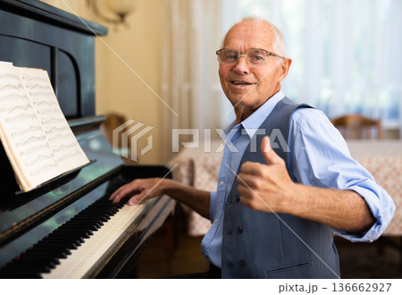 Old piano player looking in camera and showing thumb up gesture 136662927