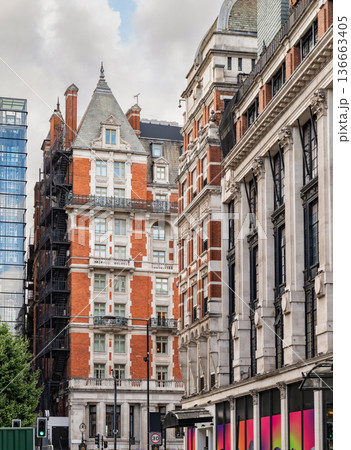 Classic British architecture lines a traditional London street, with red brick buildings and historic facades beneath a cloudy sky. Classic British architecture lines a traditional London street, with red brick buildings and historic facades beneath a cloudy sky. 136663405