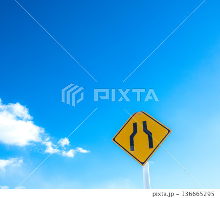 青空と雲とこの先道幅か狭いですよという道路標識のある風景 136665295