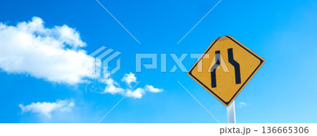 青空と雲とこの先道幅か狭いですよという道路標識のある風景 136665306