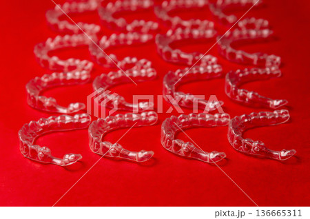 Clear aligners and braces on a colored background. Many clear hedgehog braces on a colored background. Dental background. Technological dentistry. Clear aligners and braces on a colored background. Many clear hedgehog braces on a colored background. Dental background. Technological dentistry. 136665311