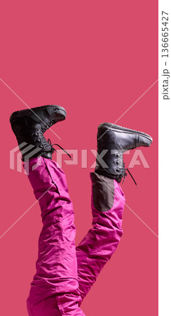 Female legs in black snow boots and pink ski pants raised on pink background. 136665427