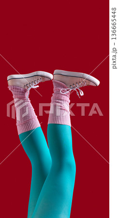 Female legs in teal tights pink leg warmers and white sneakers on red background 136665448