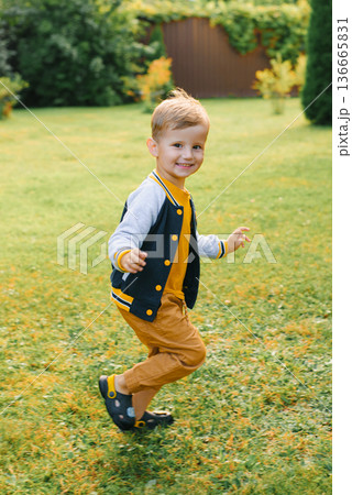 Smiling Boy Running On Green Grass Outdoors Smiling Boy Running On Green Grass Outdoors 136665831