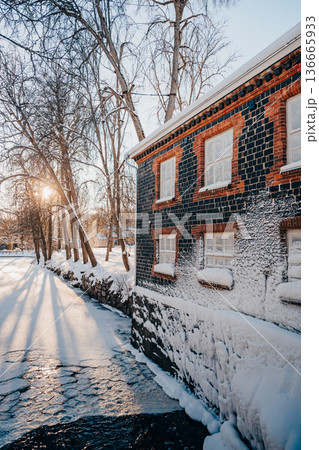 Winter riverside with historic brick building and snow at sunrise, Nordic city landscape Winter riverside with historic brick building and snow at sunrise, Nordic city landscape 136665933