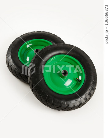 Two wheels from a garden cart on a white background. Black rubber, green disc. 136666873