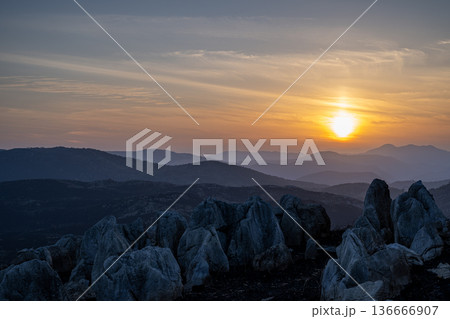 山焼き後の黒い大地に沈む夕日と石灰岩のシルエット 136666907