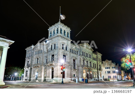 U.S. Post Office and Courthouse in Charleston, South Carolina. Historic Renaissance Revival federal building features a granite facade and corner tower illuminated at night U.S. Post Office and Courthouse in Charleston, South Carolina. Historic Renaissance Revival federal building features a granite facade and corner tower illuminated at night 136668197
