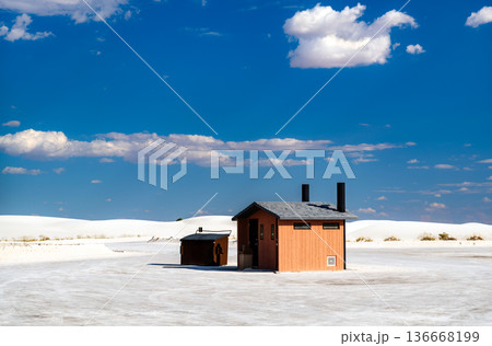White Sands National Park in New Mexico. Public wooden restroom facility building stands on the white gypsum sand dunes under a blue sky with clouds White Sands National Park in New Mexico. Public wooden restroom facility building stands on the white gypsum sand dunes under a blue sky with clouds 136668199