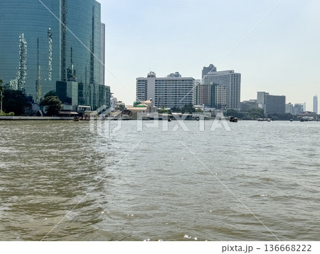 Scenic view of the Chao Phraya River in Bangkok with reflections of tall buildings and boats cruising along the water captured from the center in 2024 136668222