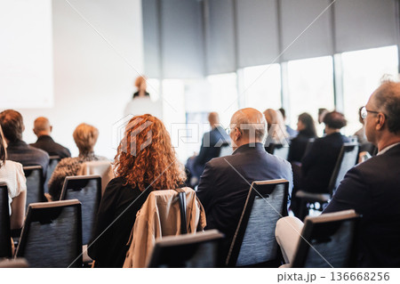 Business and entrepreneurship symposium. Female speaker giving a talk at business meeting. Audience in conference hall. Rear view of unrecognized participant in audience. Business and entrepreneurship symposium. Female speaker giving a talk at business meeting. Audience in conference hall. Rear view of unrecognized participant in audience. 136668256