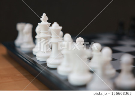 Close up of white chess pieces on board with focus on King. Strategic competition, leadership business success, management planning, marketing vision and corporate thinking challenge concept. Close up of white chess pieces on board with focus on King. Strategic competition, leadership business success, management planning, marketing vision and corporate thinking challenge concept. 136668363