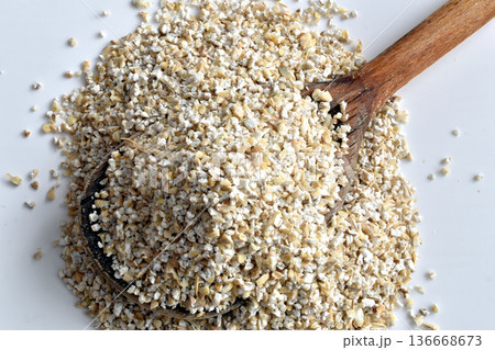 Barley groats, yachka, in a wooden spoon. Barley groats, yachka, in a wooden spoon. 136668673