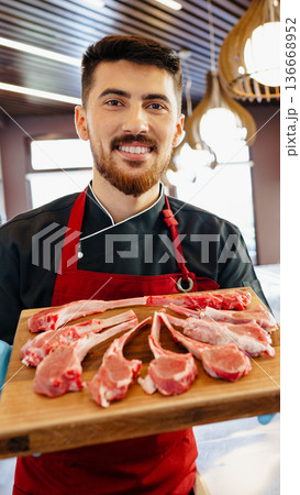 Butcher holds fresh meat cuts in a market setting during the afternoon Butcher holds fresh meat cuts in a market setting during the afternoon 136668952