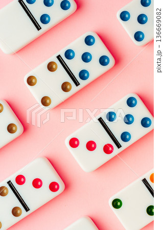 Colorful dominoes arranged on a pink surface with different dot patterns 136669082