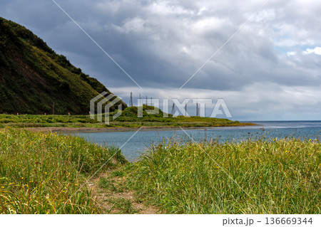 Grassy coastal path leading to calm seaside bay Grassy coastal path leading to calm seaside bay 136669344