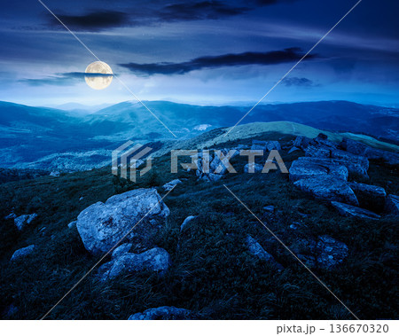 mountain landscape in summer with rocks at night. grass under dark sky in full moon light. alpine meadow and rolling hills with boulders. backdrop for evil fiction art or mystery concepts mountain landscape in summer with rocks at night. grass under dark sky in full moon light. alpine meadow and rolling hills with boulders. backdrop for evil fiction art or mystery concepts 136670320