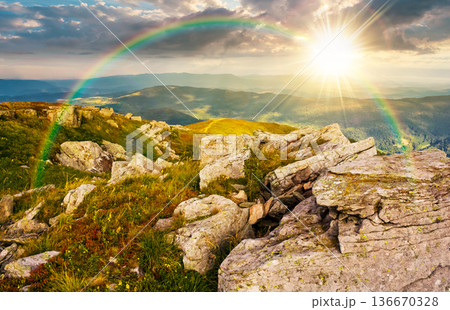 huge rocky formations on a grassy hill at sunset. wonderful mountain landscape in august in evening light. alpine scenery on a cloudy weather under the rainbow. spectacular view in to the distance huge rocky formations on a grassy hill at sunset. wonderful mountain landscape in august in evening light. alpine scenery on a cloudy weather under the rainbow. spectacular view in to the distance 136670328