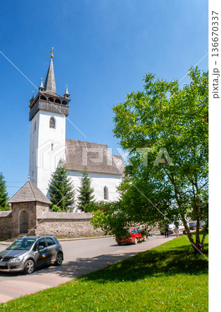 khust, ukraine - 16 jun 2012: medieval church of saint Elisabeth in downtown. building with tower behind stone masonry fence. gothic european architecture on a sunny day in summer 136670337