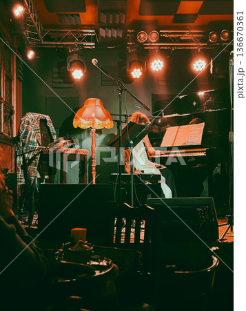 Pianist woman performing on stage with piano, concert lights, music club interior, audience silhouettes and microphone stand. Concept of live music, piano concert, performance, stage lighting in club 136670361