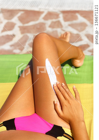Portrait of woman applying sunscreen on legs. Close-up smooth tanned legs. Portrait of woman applying sunscreen on legs. Close-up smooth tanned legs. 136671121