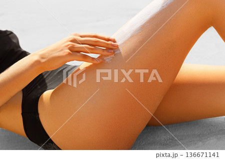 Woman applying sunscreen on her legs Woman applying sunscreen on her legs 136671141