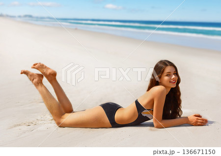 Portrait of gorgeous young woman smiling while relaxing on beach Portrait of gorgeous young woman smiling while relaxing on beach 136671150