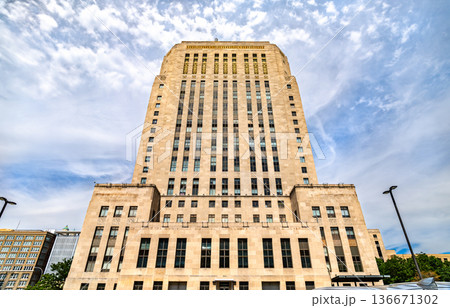 Kansas City City Hall in Missouri. Historic Art Deco government building features a tall limestone facade and vertical windows under a blue sky with clouds 136671302