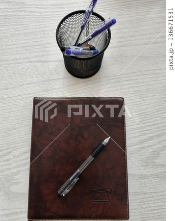 Routine office items: phone book and pen on wooden table 136671531