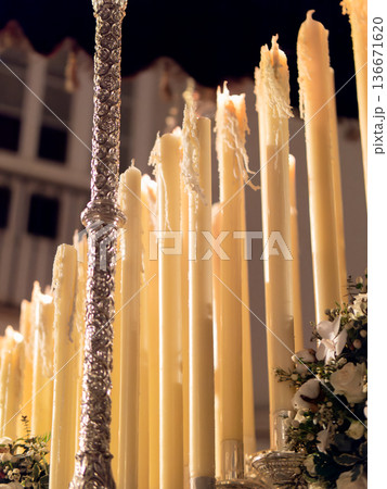 Close up of many tall wax candles burning on a religious processional float at night Close up of many tall wax candles burning on a religious processional float at night 136671620