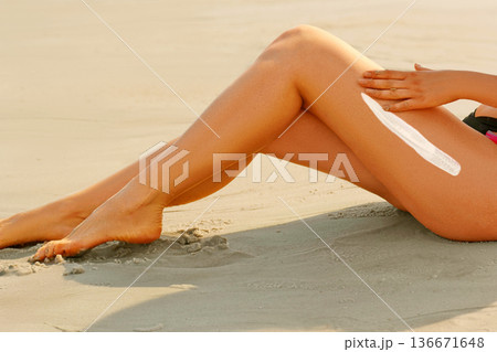 Portrait of woman applying sun protection cream at beach 136671648