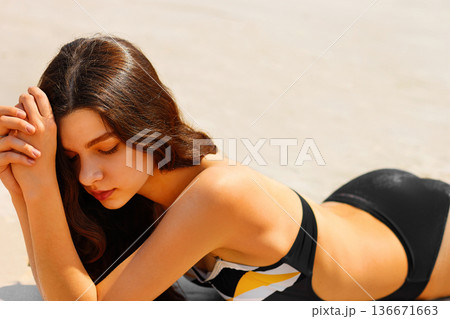 Portrait of a sensual young lady having tanning on the beach 136671663