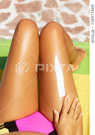 Cropped shot of a young woman applying sunscreen to her legs while. Sunscreen on legs. Cropped shot of a young woman applying sunscreen to her legs while. Sunscreen on legs. 136671668