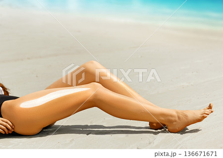 Woman applying sunscreen on her legs 136671671