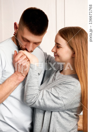 Couple shares a moment in the kitchen as man kisses womans hand in a cozy home setting during a casual afternoon 136671768