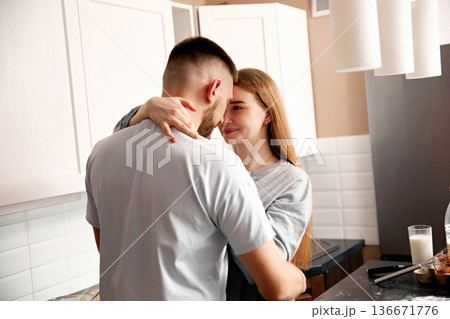 Couple shares a moment in the kitchen while cooking together in a modern home during the afternoon Couple shares a moment in the kitchen while cooking together in a modern home during the afternoon 136671776