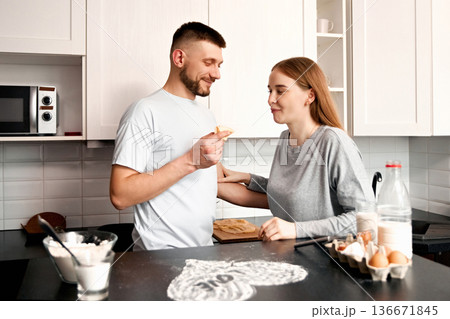 Couple prepares food together in a kitchen while sharing a moment and enjoying homemade treats on a weekend morning Couple prepares food together in a kitchen while sharing a moment and enjoying homemade treats on a weekend morning 136671845
