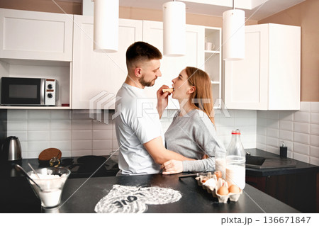 Couple enjoys cooking together in the kitchen while sharing a light moment with food during a sunny afternoon Couple enjoys cooking together in the kitchen while sharing a light moment with food during a sunny afternoon 136671847