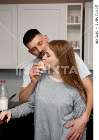 Couple shares a joyful moment in the kitchen while enjoying a snack at home during an afternoon 136671850