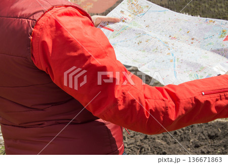 Woman in a red jacket holding cards while traveling, trip 136671863