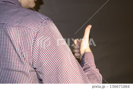 the young man turned away and shows the sign OK, fingers up, shadow on the wall. the young man turned away and shows the sign OK, fingers up, shadow on the wall. 136671868