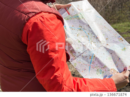 Woman in a red jacket holding cards while traveling, trip Woman in a red jacket holding cards while traveling, trip 136671874