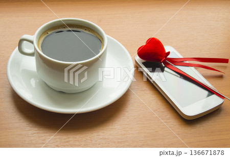 Cup of coffee, the smartphone with red heart on a wooden table Cup of coffee, the smartphone with red heart on a wooden table 136671878