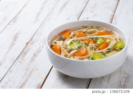 Homemade chicken soup in white bowl with carrots and celery 136672109