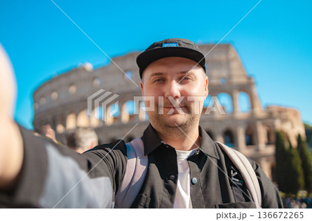 Handsome 30s tourist visiting Colosseum in Rome, Italy. Young man taking photo in front of famous Italian landmark Handsome 30s tourist visiting Colosseum in Rome, Italy. Young man taking photo in front of famous Italian landmark 136672265