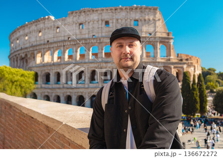 Handsome 30s tourist visiting Colosseum in Rome, Italy. Young man taking photo in front of famous Italian landmark  136672272